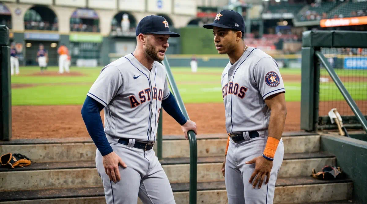 Dos jugadores de Houston permanecen cerca del dugout mientras observan el terreno de béisbol bajo las luces del estadio.